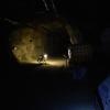 A SPOT robot with a light enters a dark mine tunnel