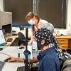 Rosy Southwell and Cooper Steputis demonstrate the use of a functional near-infrared spectroscopy device in D'Mello's lab