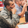 photo of man in camouflage military attire and other students in a classroom