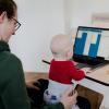 A woman works at her computer with her baby in her lap