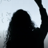 Woman backlit against math-filled smartboard