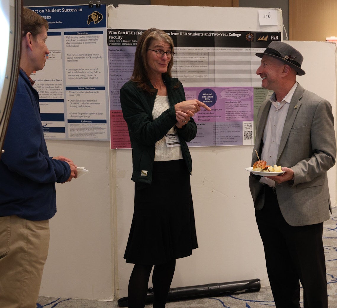 Presenters discuss an REU poster