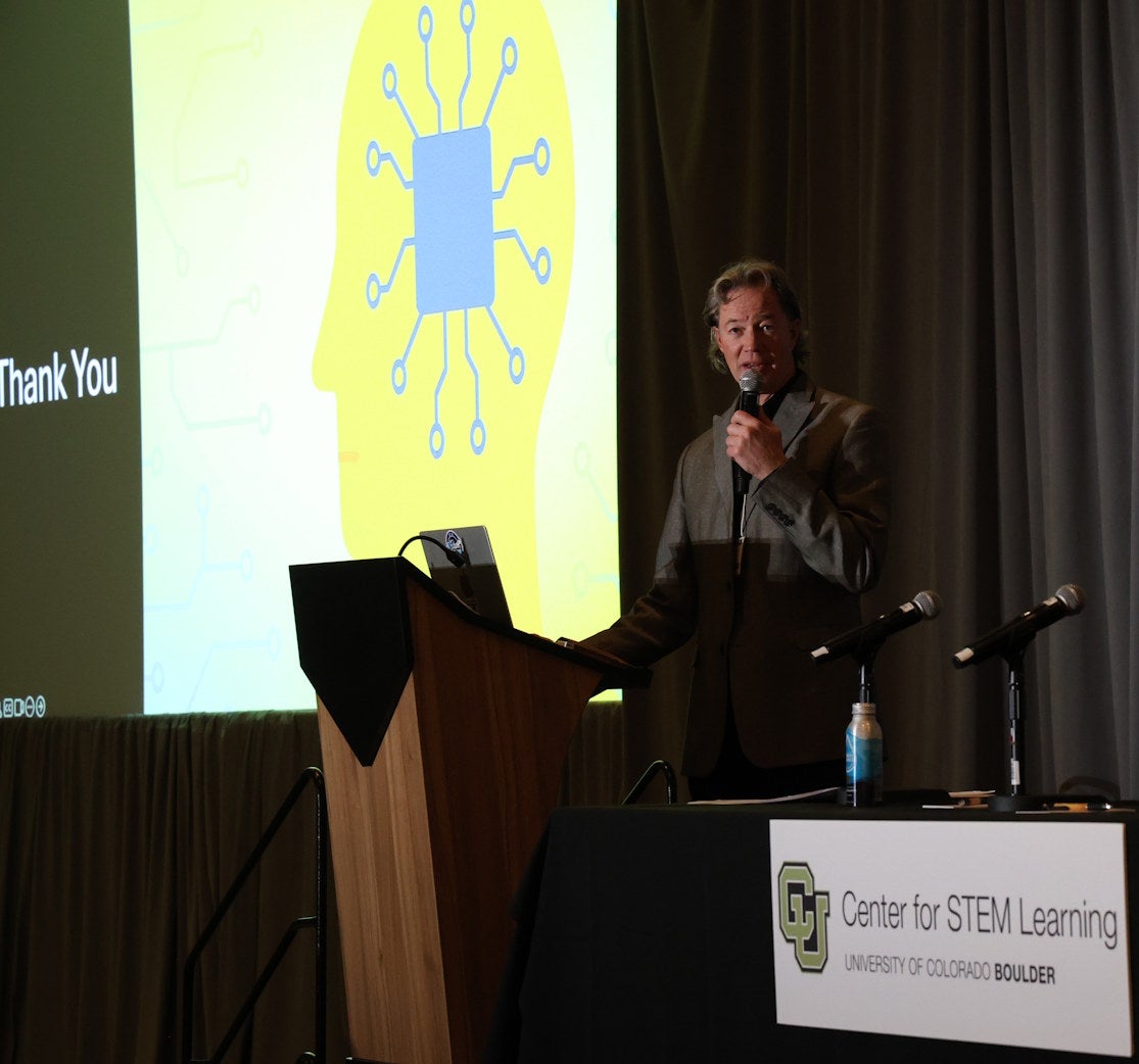 Brad McClain thanks the audience from the stage near a CSL logo and an image representing AI