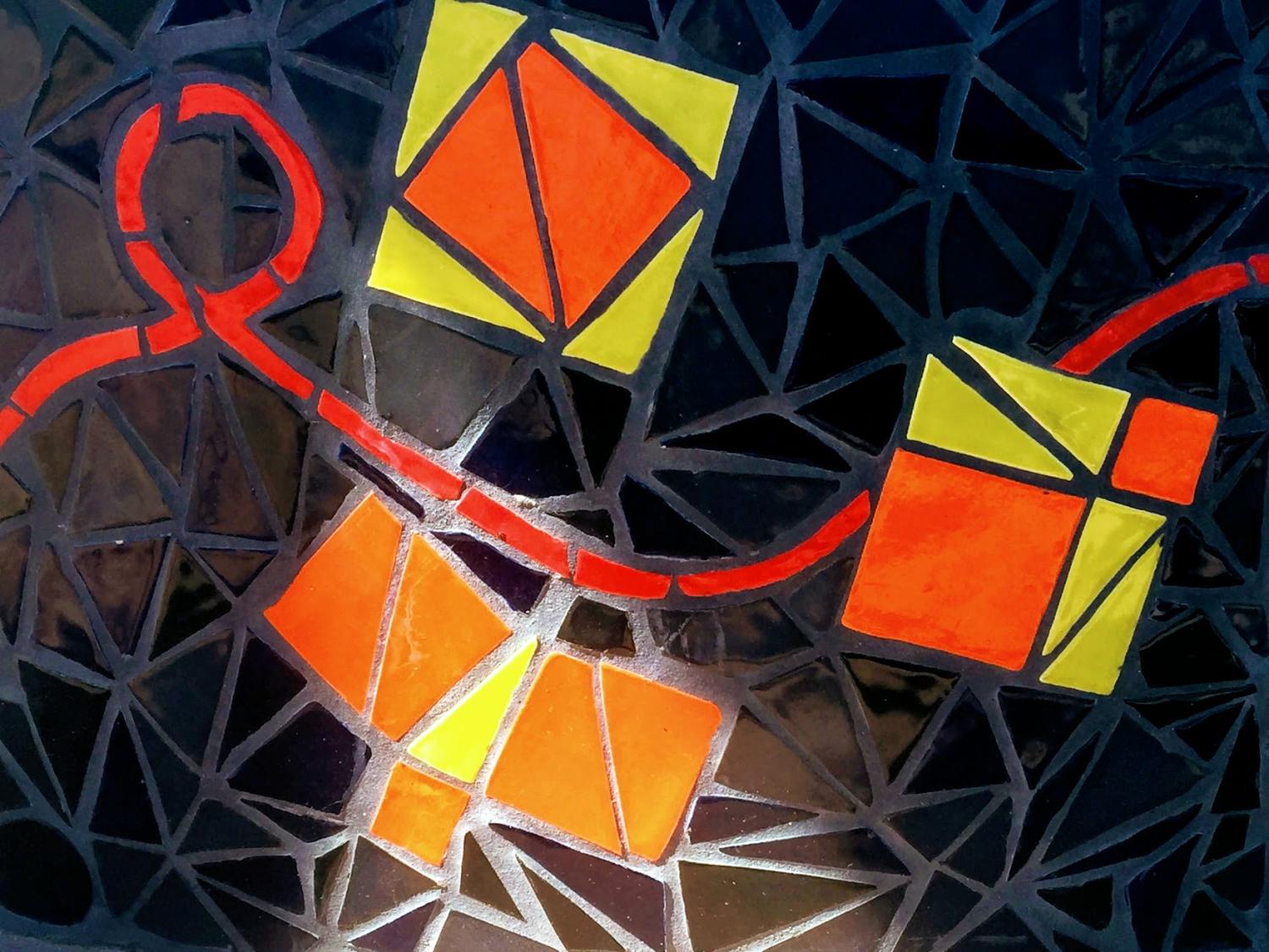 Mosaic Tiles, black background. showing yellow and orange triangles and squares with red ribbon running thru