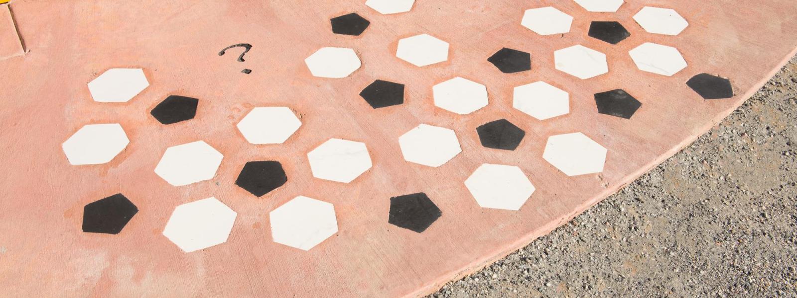 A group of white and black hexagons are seen on a red rock background.