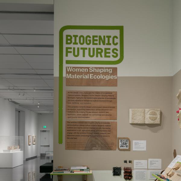 A gallery with many different objects, including bricks and other building materials, installed on or beneath wooden shelves.