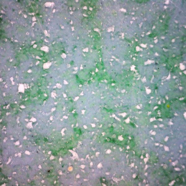 highly magnified detail of a resign object with greens and blues