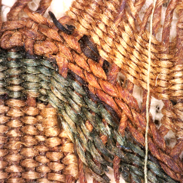 highly magnified detail of a woven cloth with red and green pigments visible