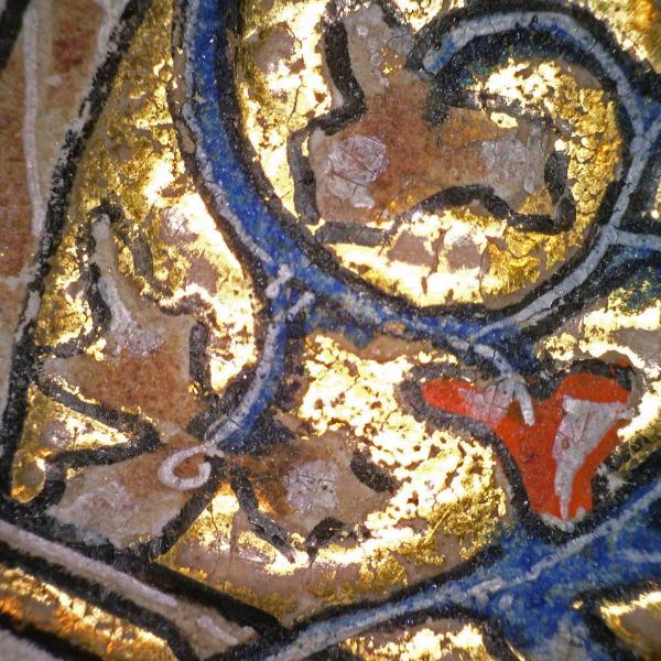 highly magnified detail of a manuscript page with bright gold, blue, and red shapes