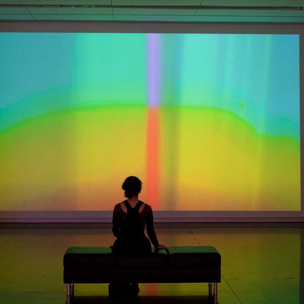 Woman sitting in front of projected image of color