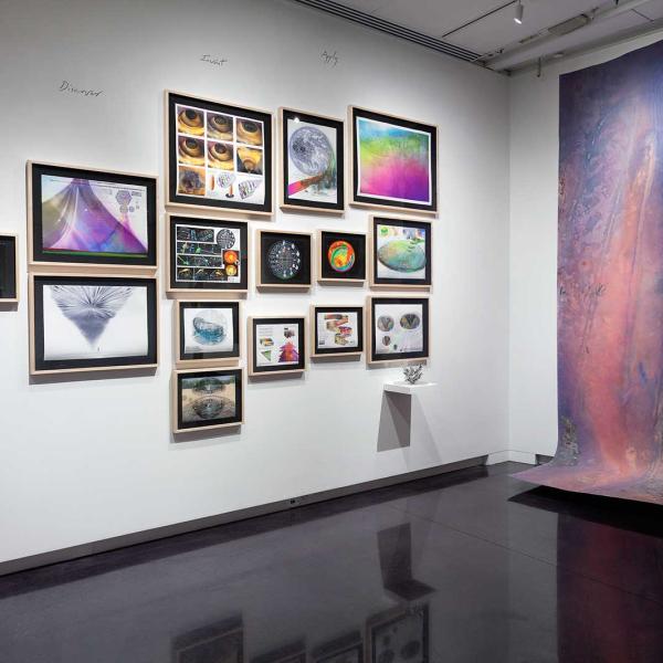 Paintings hung in a cluster on the wall of the gallery.