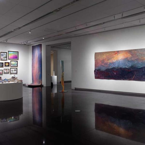 A view of the gallery with sculptures on pedestals and paintings on the walls.