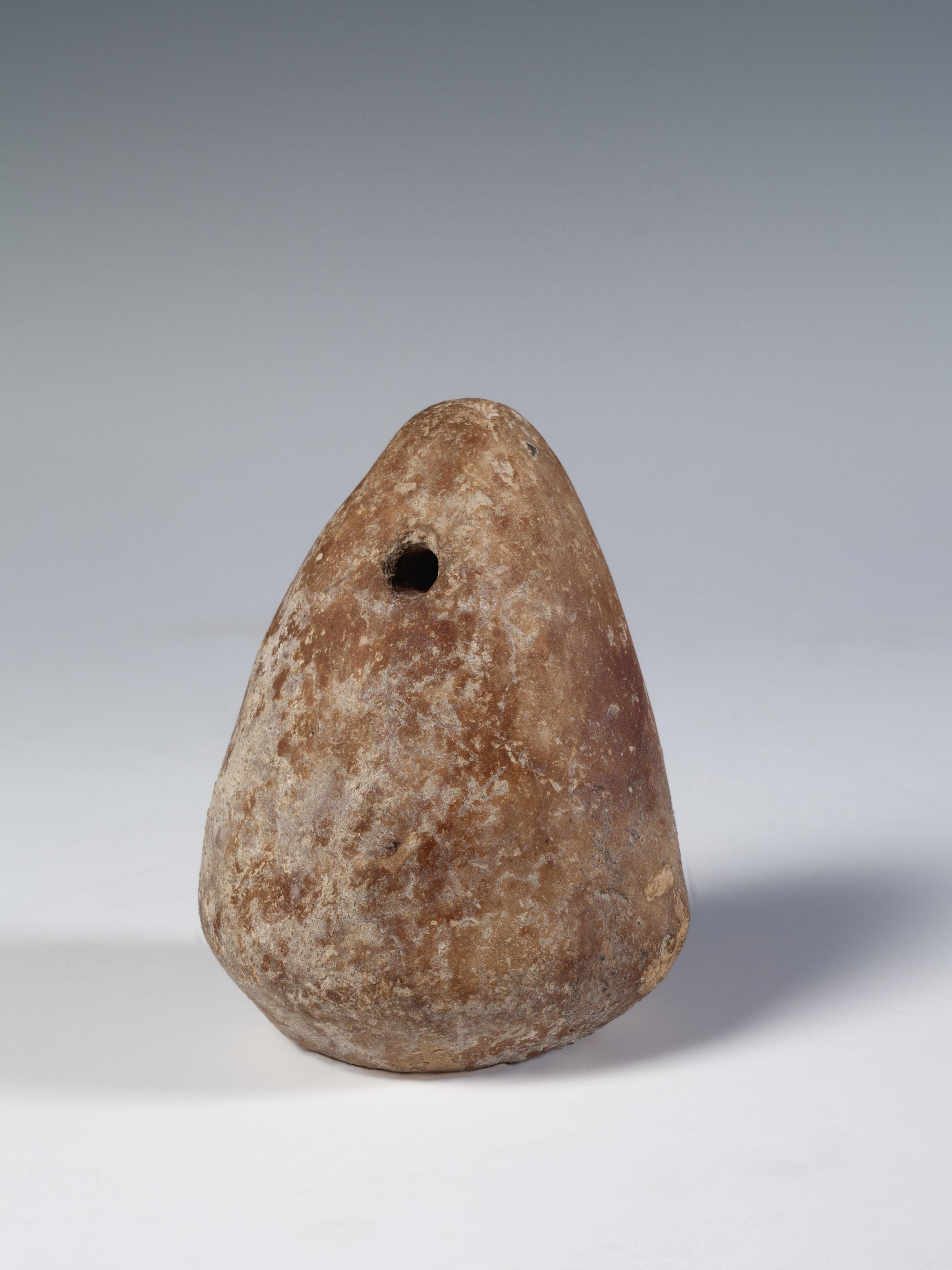 rounded triangle of reddish stone with a hole drilled in the top