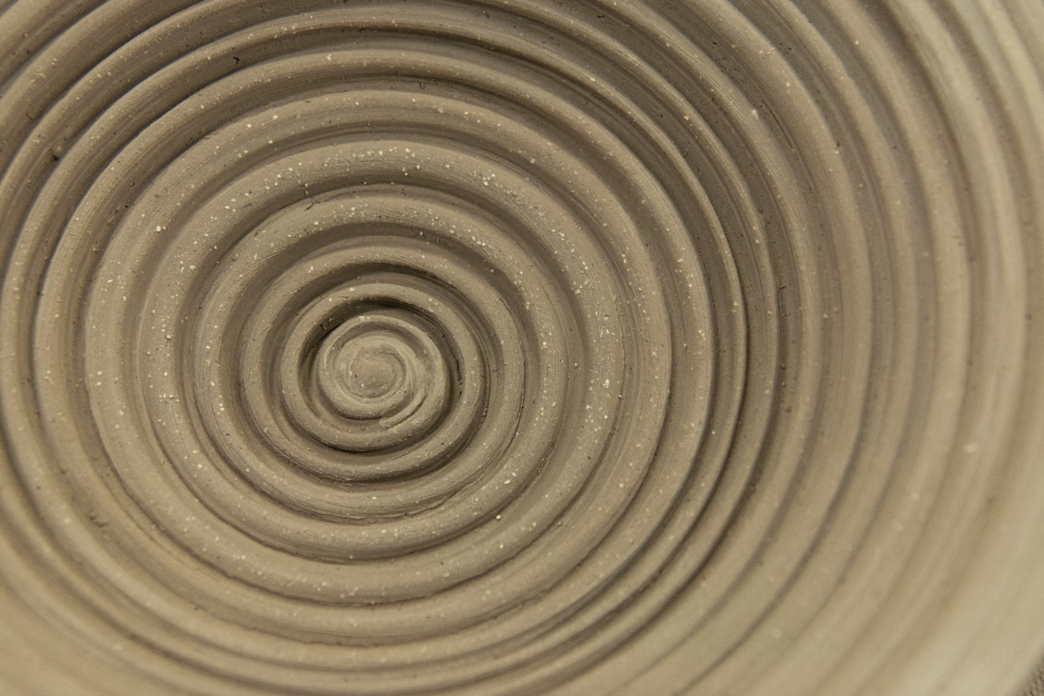 A close up photo of a clay sculpture with a spiral pattern carved into it.