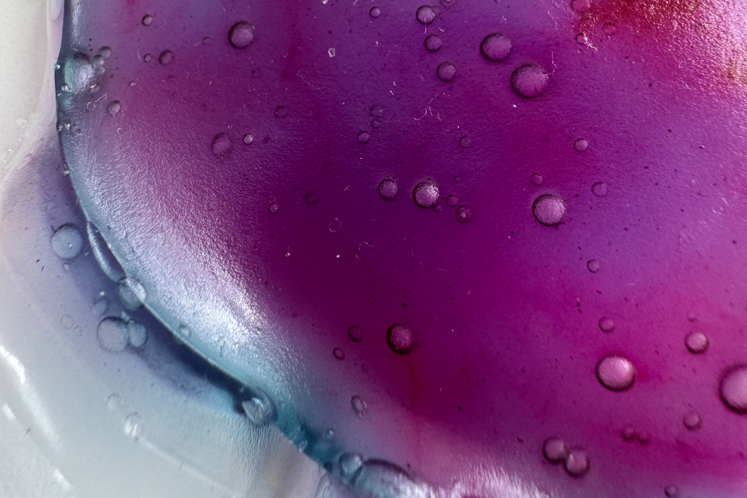 Close up of some purple and blue liquid with bubbles in it.