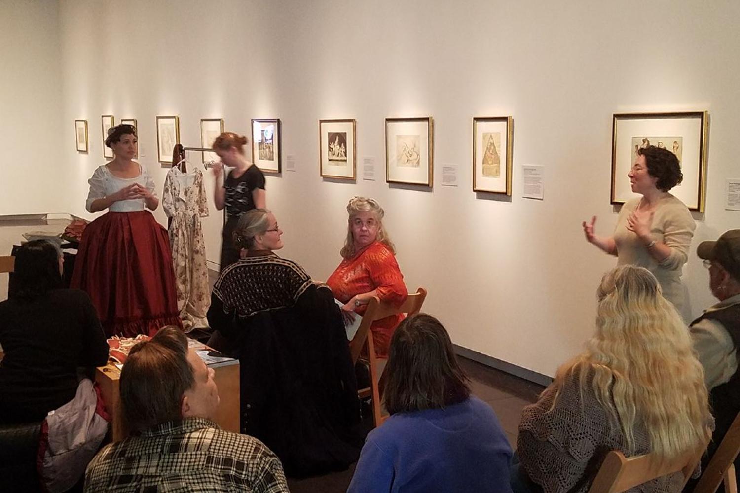 Women speaking in an exhibition of prints