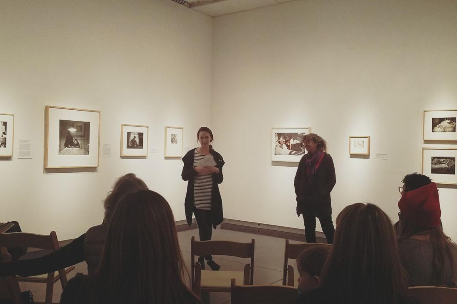 Women speaking in an exhibition of photographs