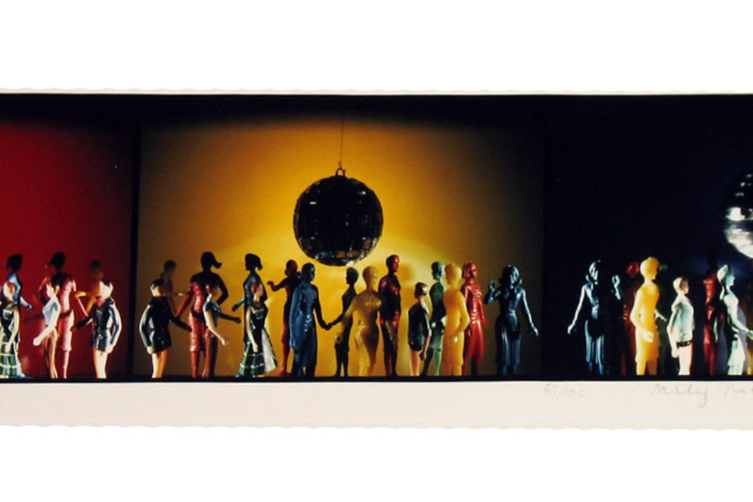 Many colorful plastic figurines of people standing in a colorful room with disco balls.