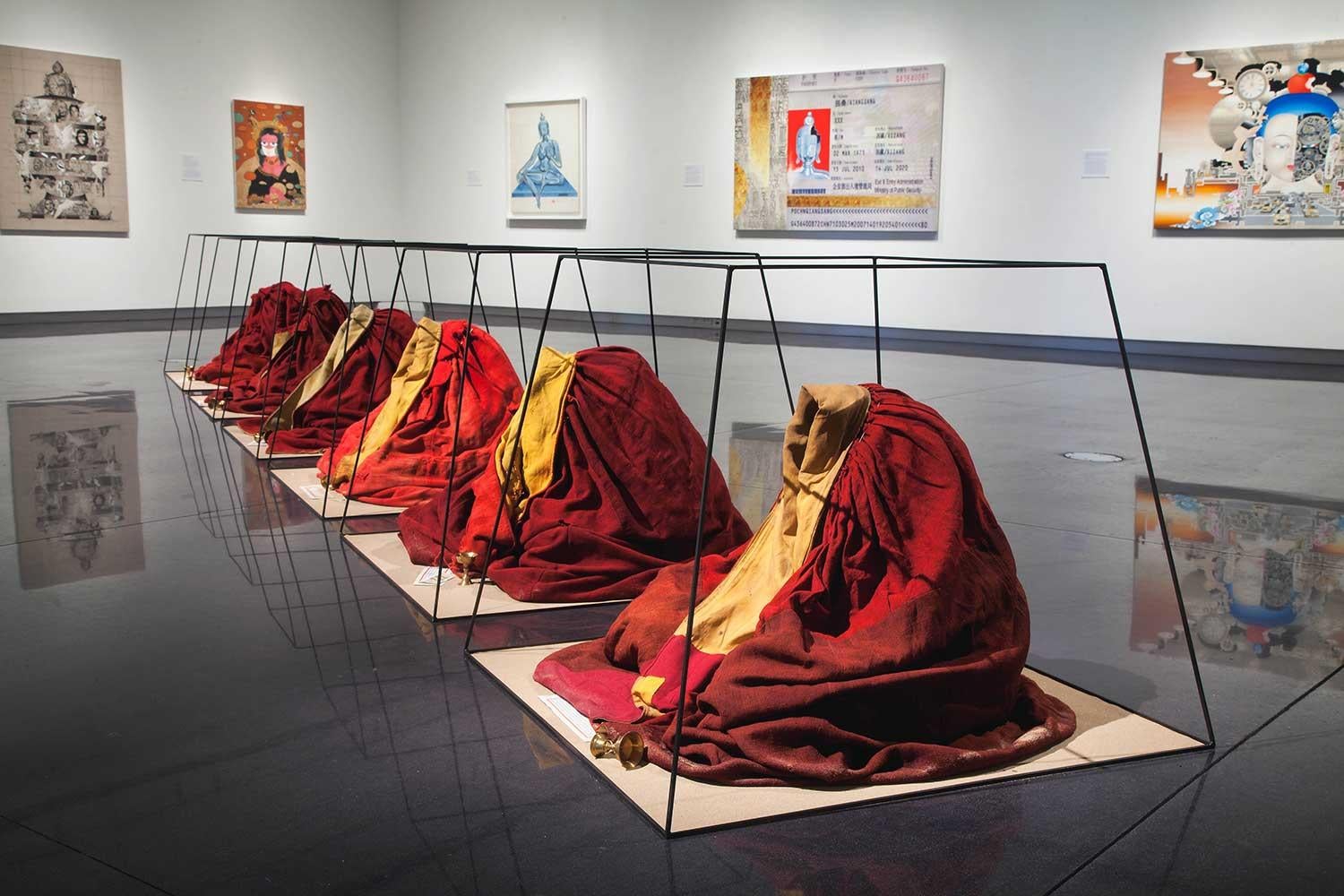 Installation view of the exhibition Anonymous: Contemporary Tibetan Art, in the CU Art Museum, showing installation of monks robes and paintings