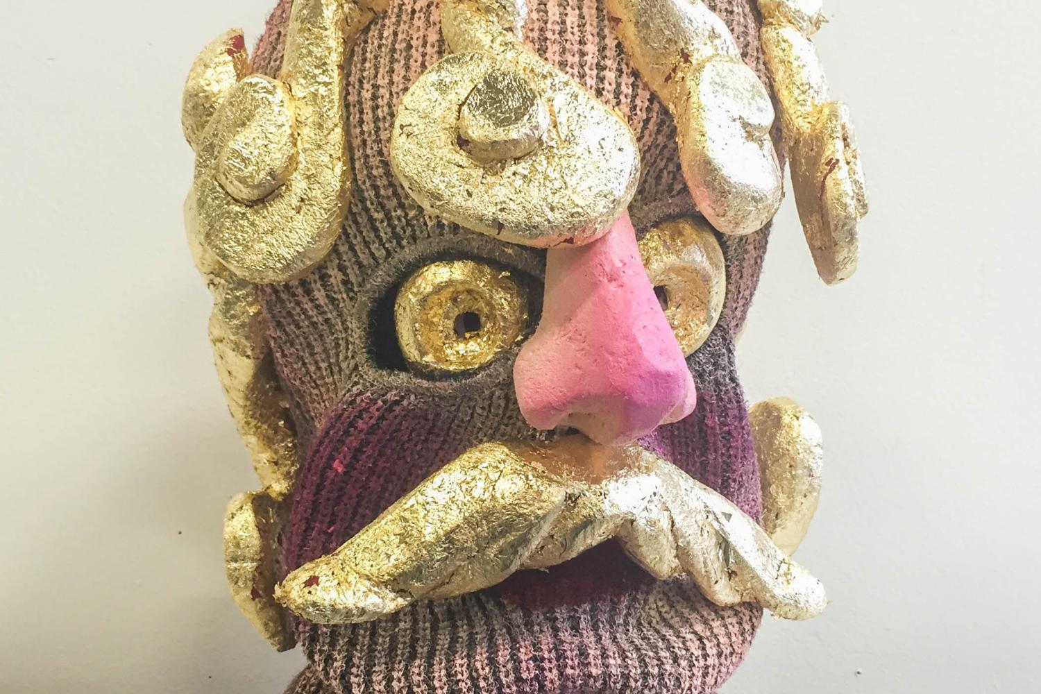 a knit mask covered in ceramic gold spirals