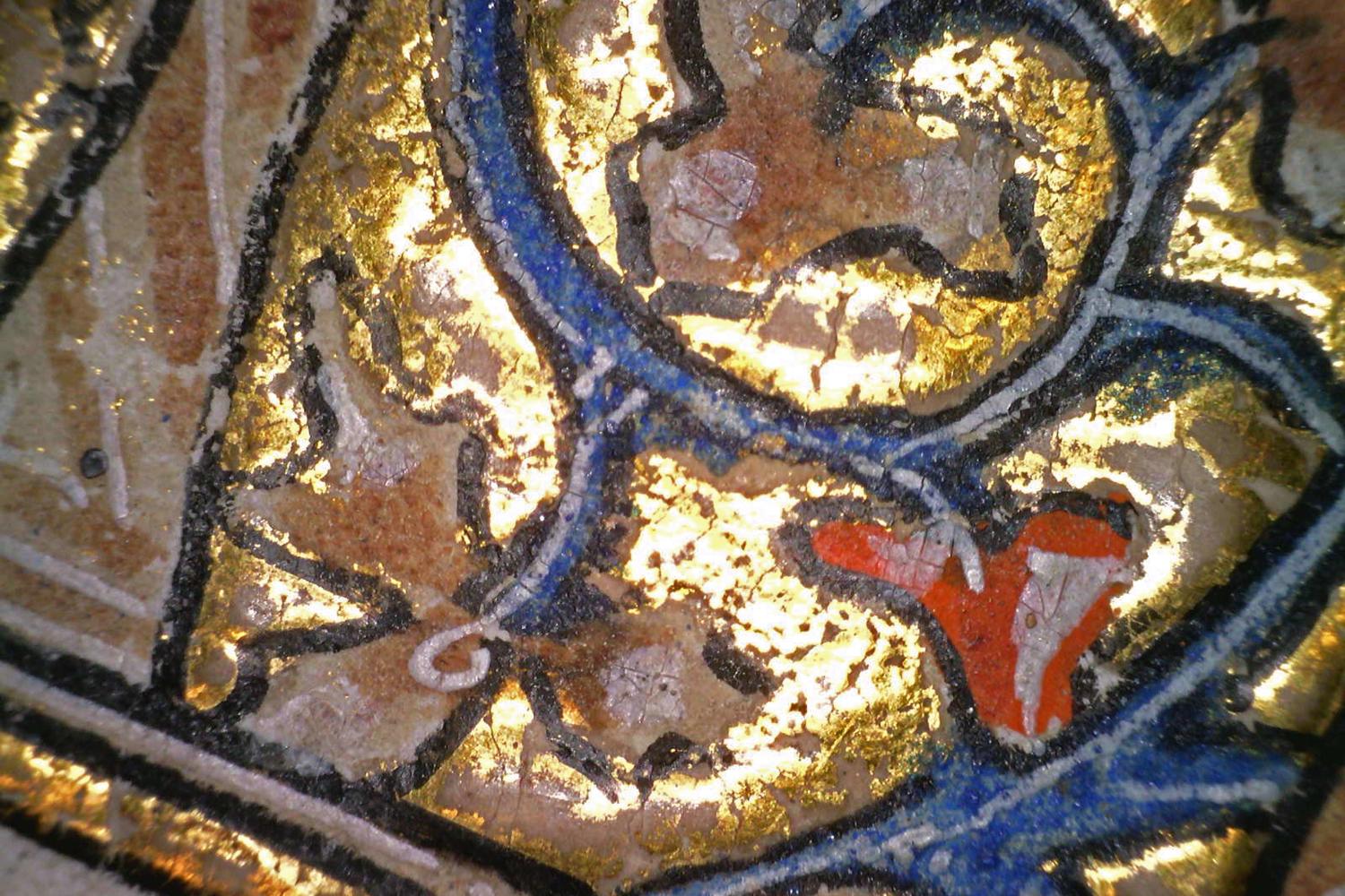 highly magnified detail of a manuscript page with bright gold, blue and red shapes