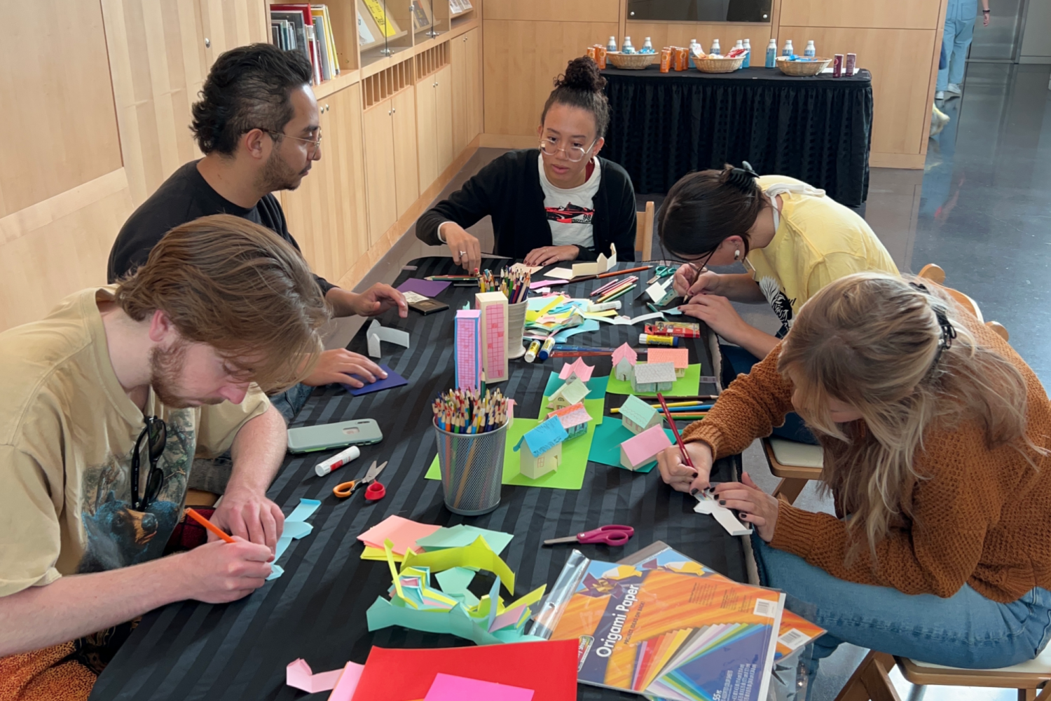 Many students building paper houses together in the CU Art Museum lobby.