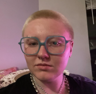 Neb, a white person with a short blonde buzzcut and light blue glasses.