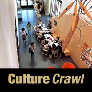 An arial view of the CU Art Museum lobby. Many people are gathered at a table while making art together, and a large metal and wood sculpture is suspended from the ceiling in the foreground. At the bottom in gold letters on a black background reads, "Culture Crawl".