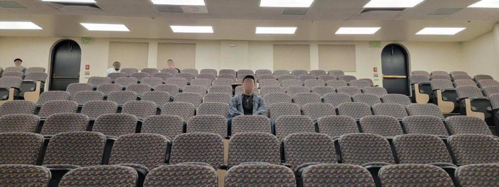 Student alone in auditorium seats in classroom