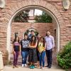 Small group of students and faculty standing under archway outside building