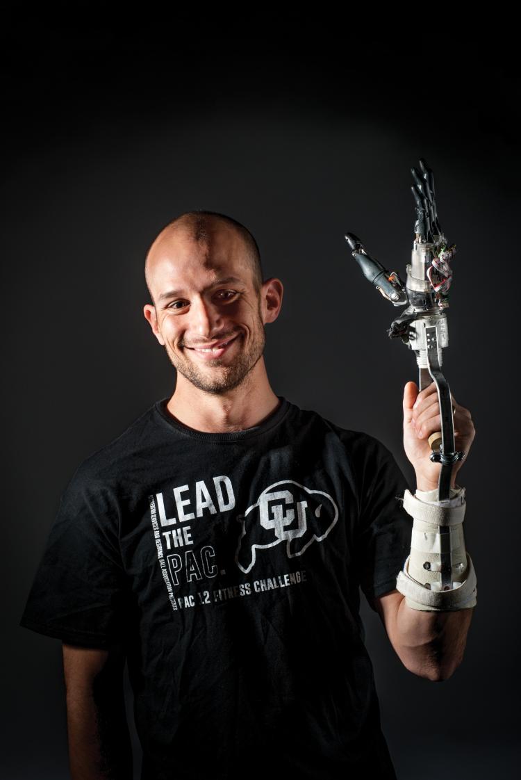 Researcher, Jacob Segil, holding the prosthetic arm he created proudly. 