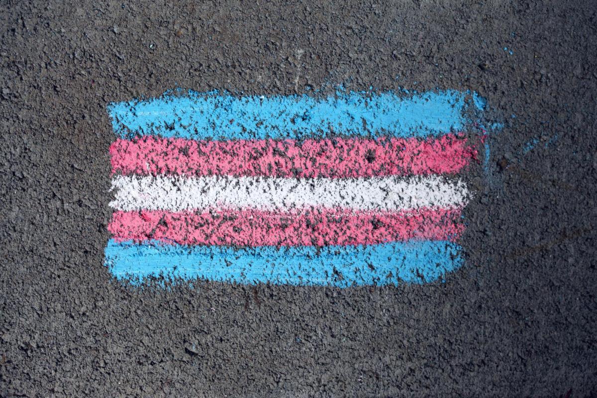 A chalk drawing of the transgender flag on asphalt.