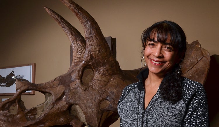Headshot of Karen Chin in Paleo Hall, next to a Triceratops skull