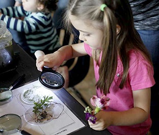 Girl looking at plants with magnifying glass