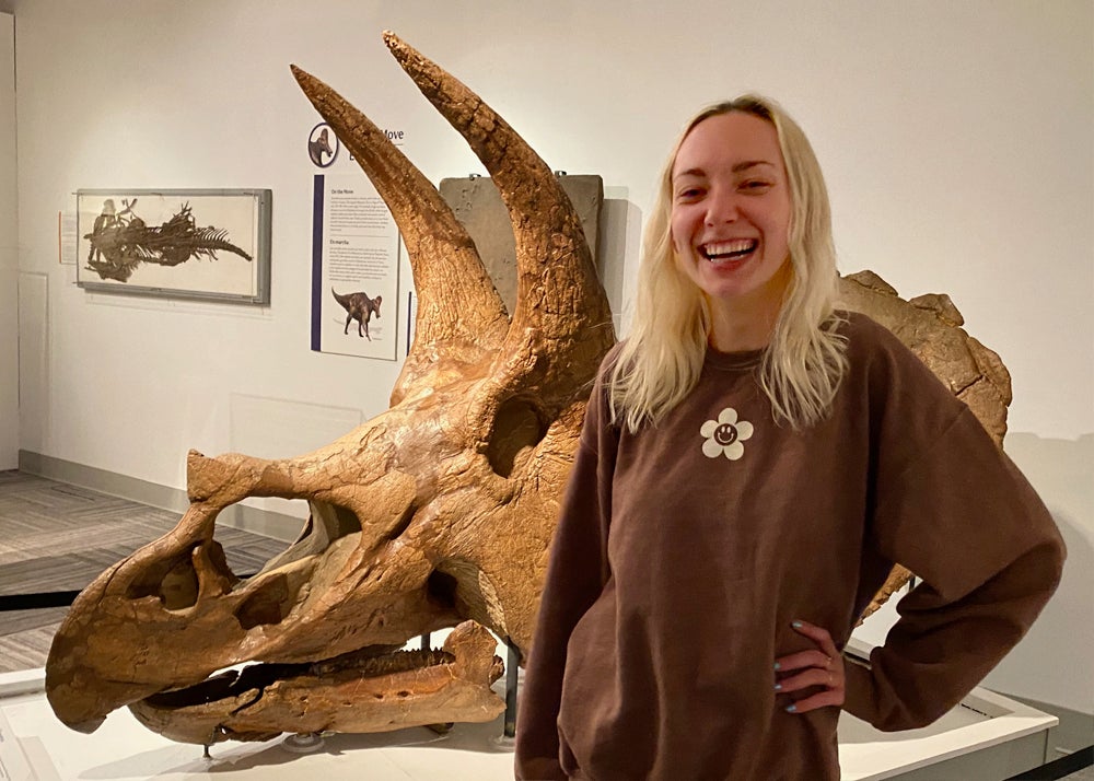 Rachel Shea standing in front of triceratops skull in paleontology hall