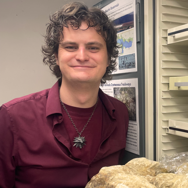 Casey Thater with specimen in front of open collections cabinet