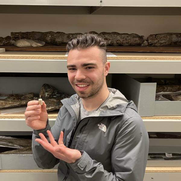 Joel Crothers holding specimen in front of collection shelves