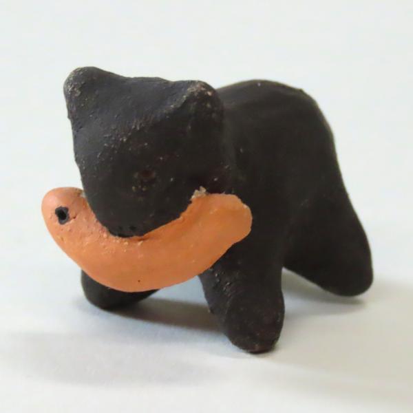 clay black bear holding orange fish in his mouth