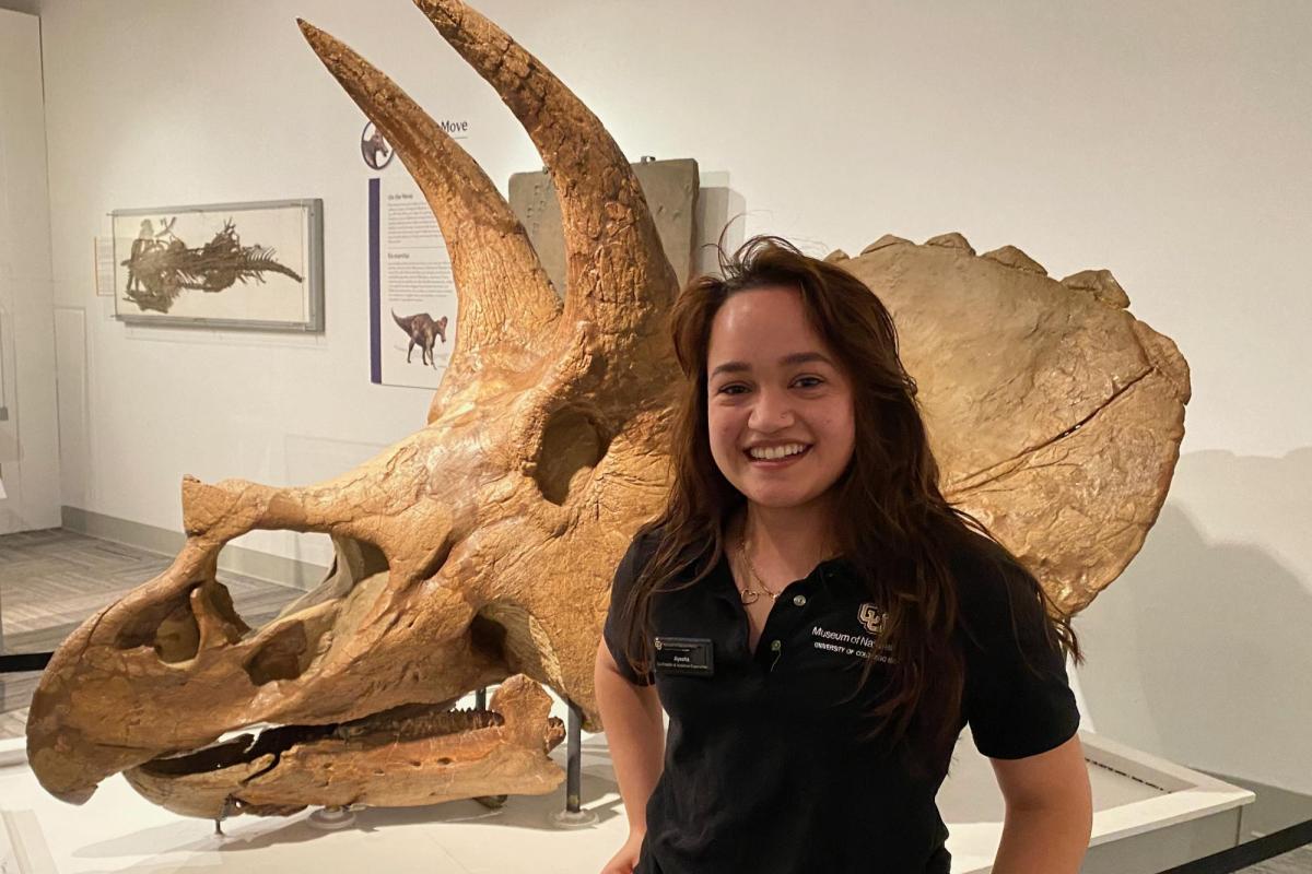 Ayesha Rawal standing in front of triceratops skull in Paleontology Hall