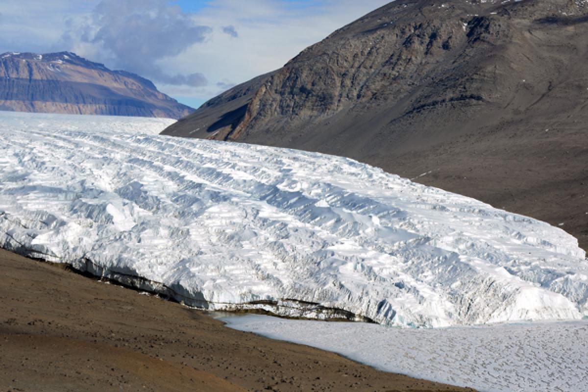 Glacier with mountain behind and brown soil below