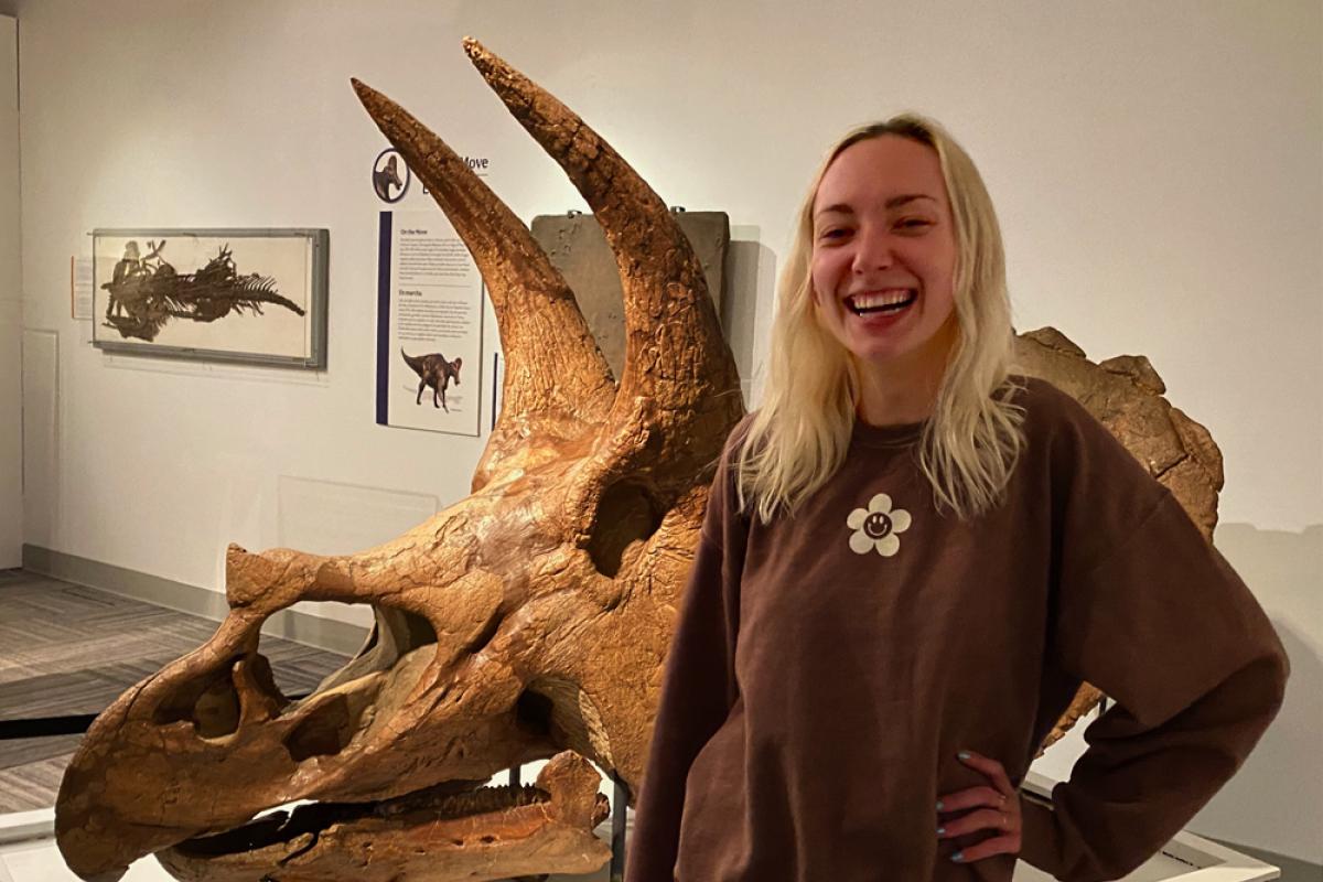 Rachel Shea standing in front of triceratops skull in Paleontology Hall