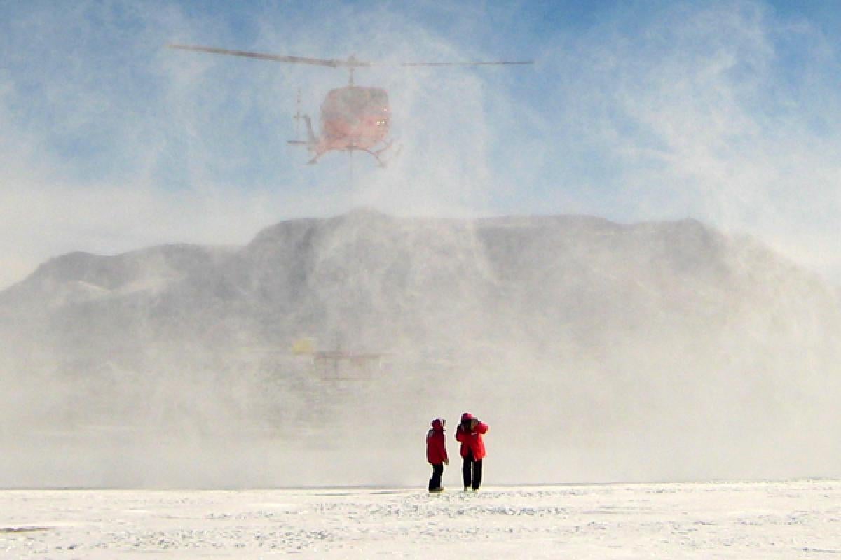 researchers getting dropped off by helicopter in a barren ice field