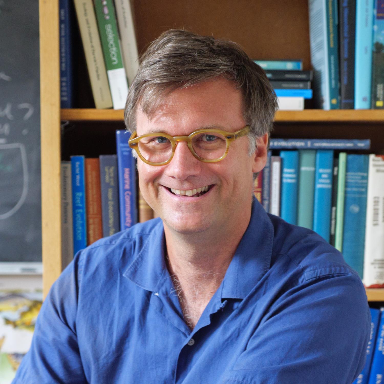 Carl Simpson sitting in front of a bookshelf in his office