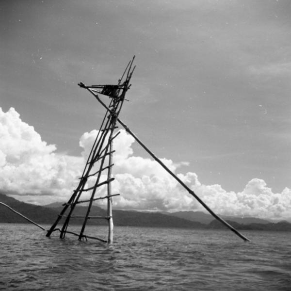 Tower constructed of long wooden poles, standing in the ocean.