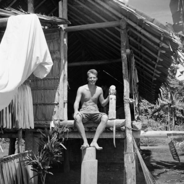 Bud johnson sitting on porch next to wood carving of woman about three feet high