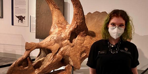 Emily Howard standing in front of triceratops skull in Paleontology Hall