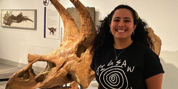 Hope Fox standing in front of triceratops skull in Paleontology Hall