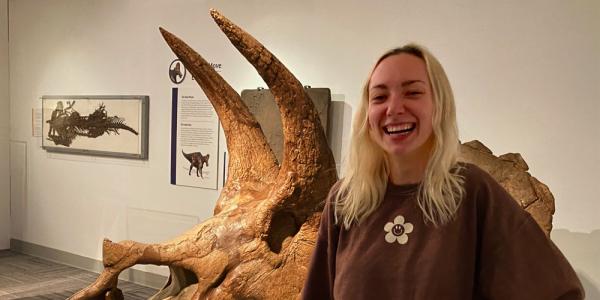 Rachel Shea standing in front of triceratops skull in Paleontology Hall