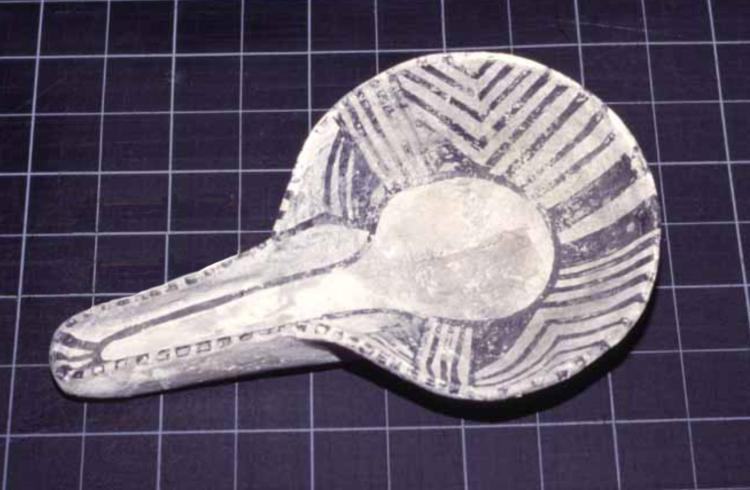 A geometrically patterned black and white ladle made of clay. The right edge of the ladle is slightly more worn down than the left side.