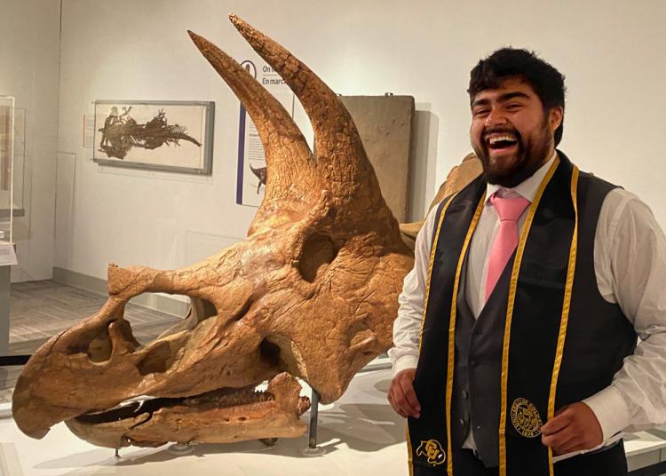 José Manriquez-Hernandez standing in front of the triceratops skull in paleontology hall